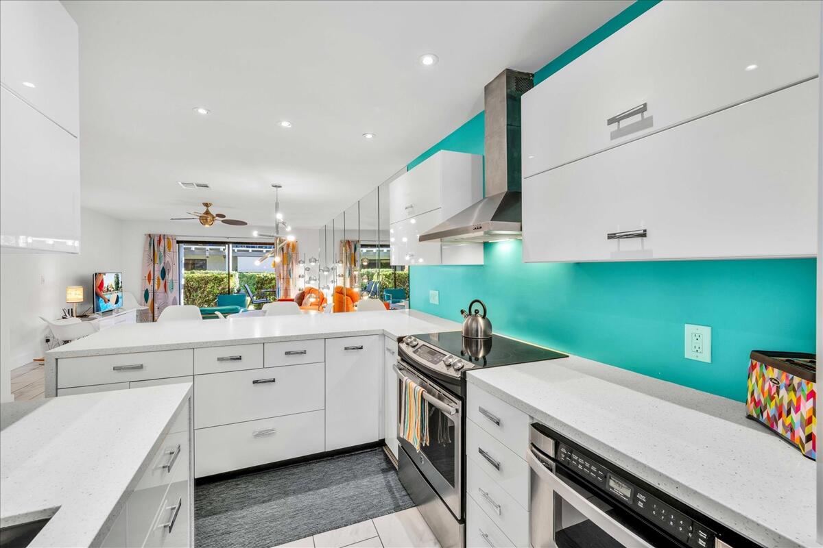 1050 Ramon Road, Unit 110 Palm Springs, CA 92264 - Photo 6 of 28 a kitchen with a sink dishwasher and white cabinets with wooden floor