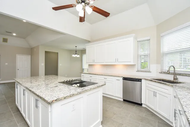 a kitchen with granite countertop cabinets a sink a stove and a refrigerator