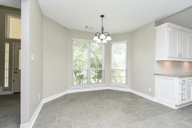 a view of an empty room with window and chandelier