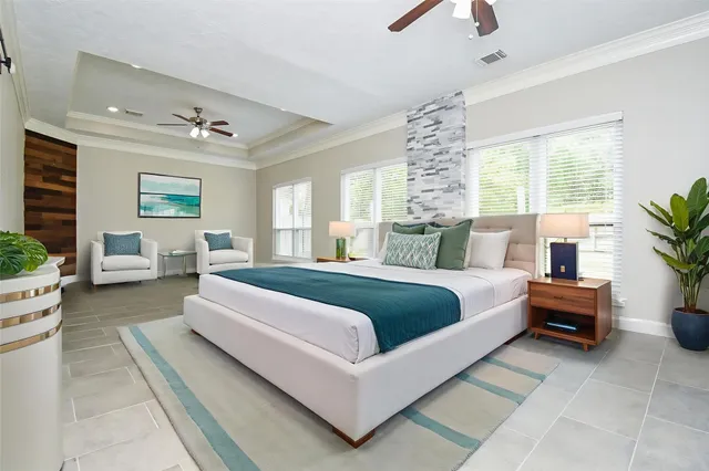 a bedroom with a large bed and a chandelier fan