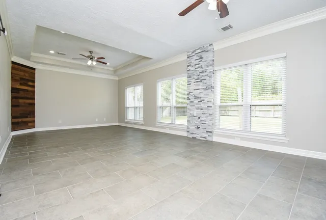 a view of an empty room with chandelier fan and fire place