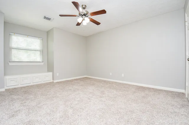 an empty room with a window and a fan