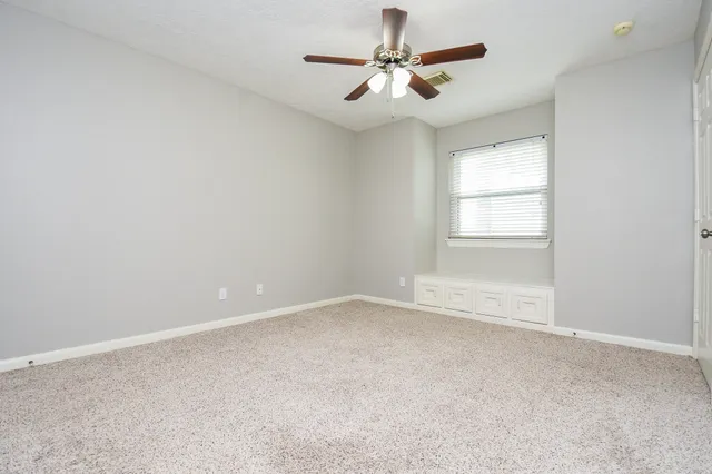 an empty room with a window and a fan