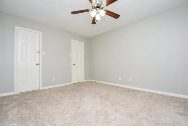 a view of an empty room and chandelier fan