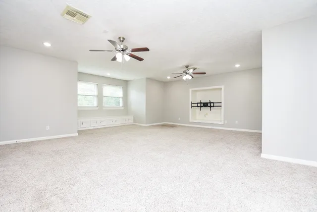 an empty room with windows and ceiling fan
