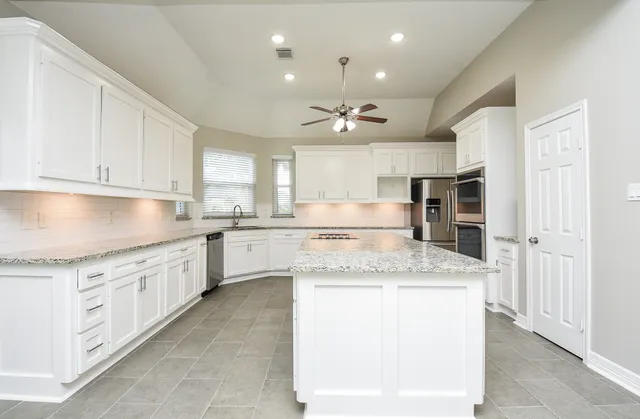 a kitchen with stainless steel appliances granite countertop a sink counter space cabinets and a large window