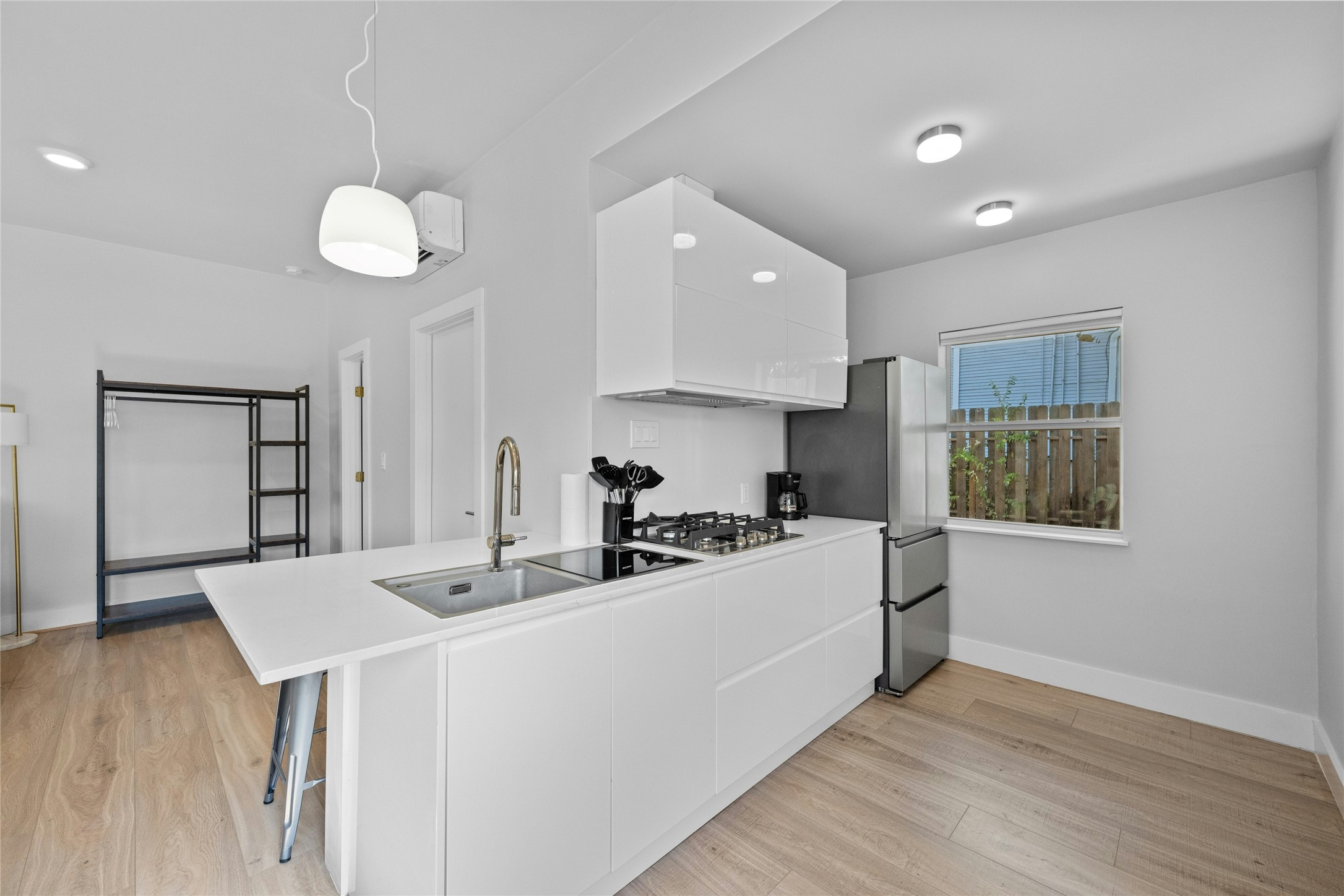 2201 Leon Street, Unit D Austin, TX 78705 - Photo 11 of 24 Kitchen with pendant lighting, white cabinetry, sink, kitchen peninsula, and a breakfast bar