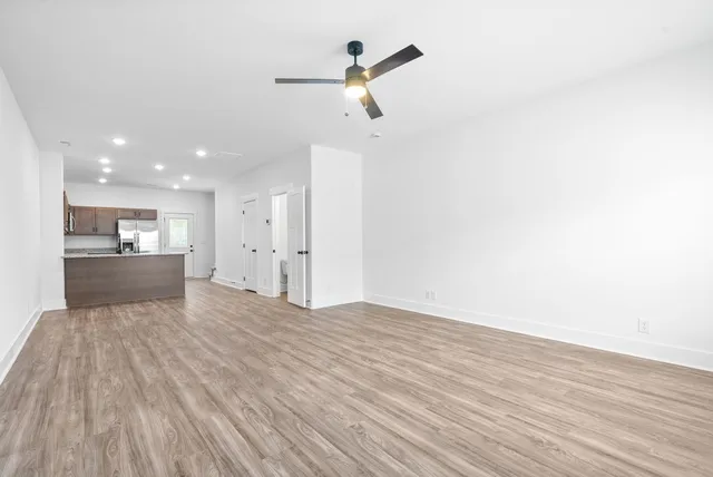 a view of kitchen and empty room with wooden floor