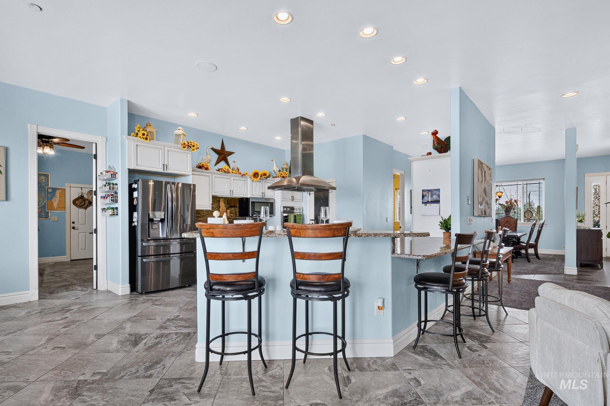 11378 Purple Sage Road Middleton, ID 83644 - Photo 12 of 50 Kitchen featuring a central island with a gooseneck faucet, light cabinetry with dark hardware, stone countertops, and tile flooring