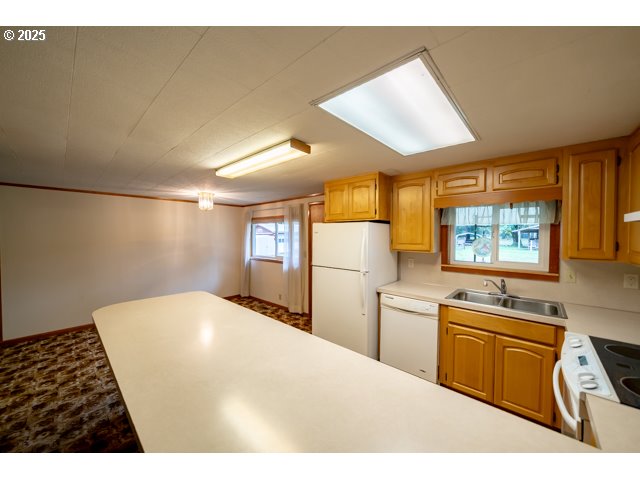 628 13th Street Lyons, OR 97358 - Photo 10 of 32 a kitchen with stainless steel appliances a stove a sink a refrigerator white cabinets and wooden floor