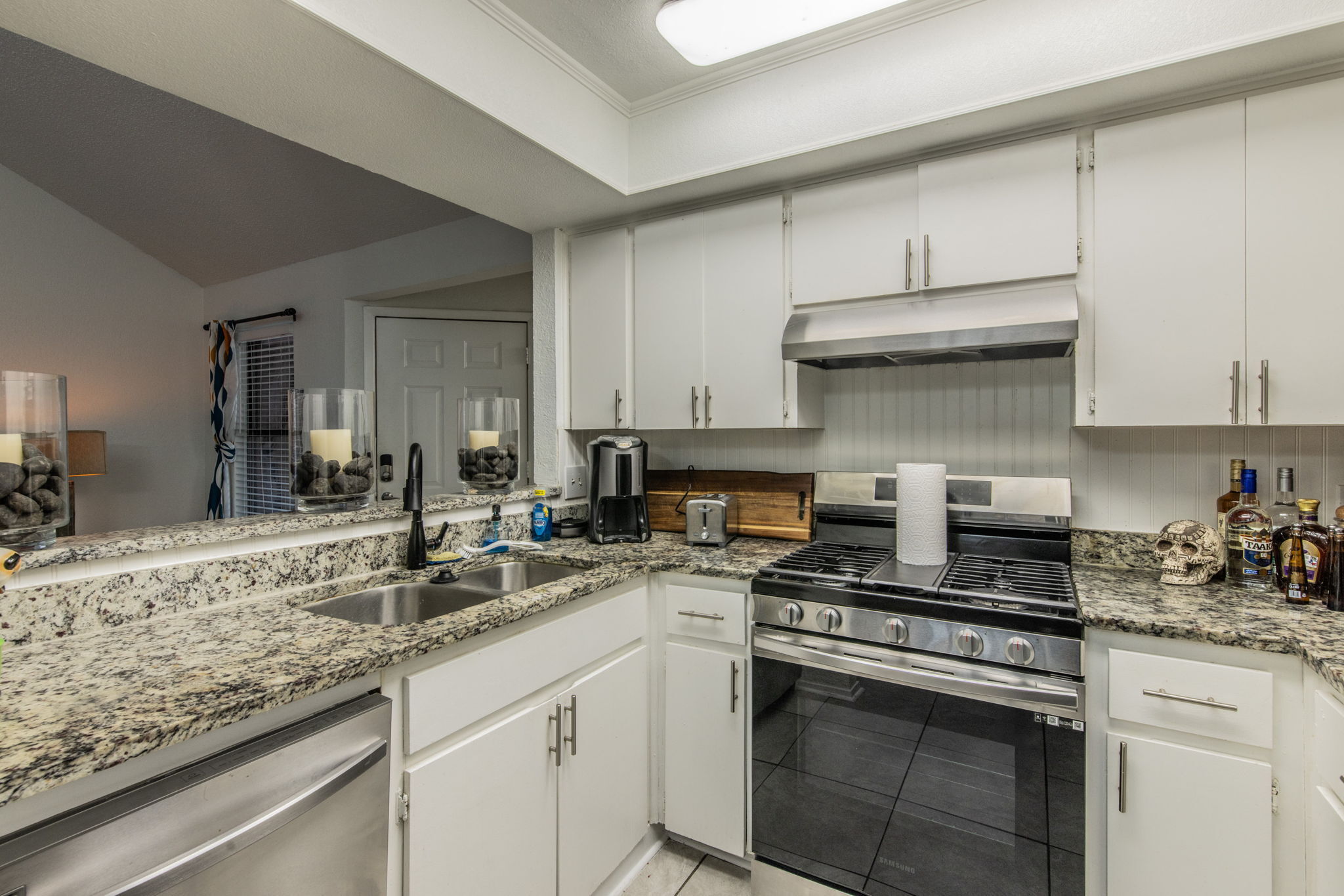 1008 Milford Way Austin, TX 78745 - Photo 26 of 40 Kitchen featuring granite countertops, white cabinetry, a double basin sink with a black faucet, a stainless steel gas range, and a stainless steel dishwasher