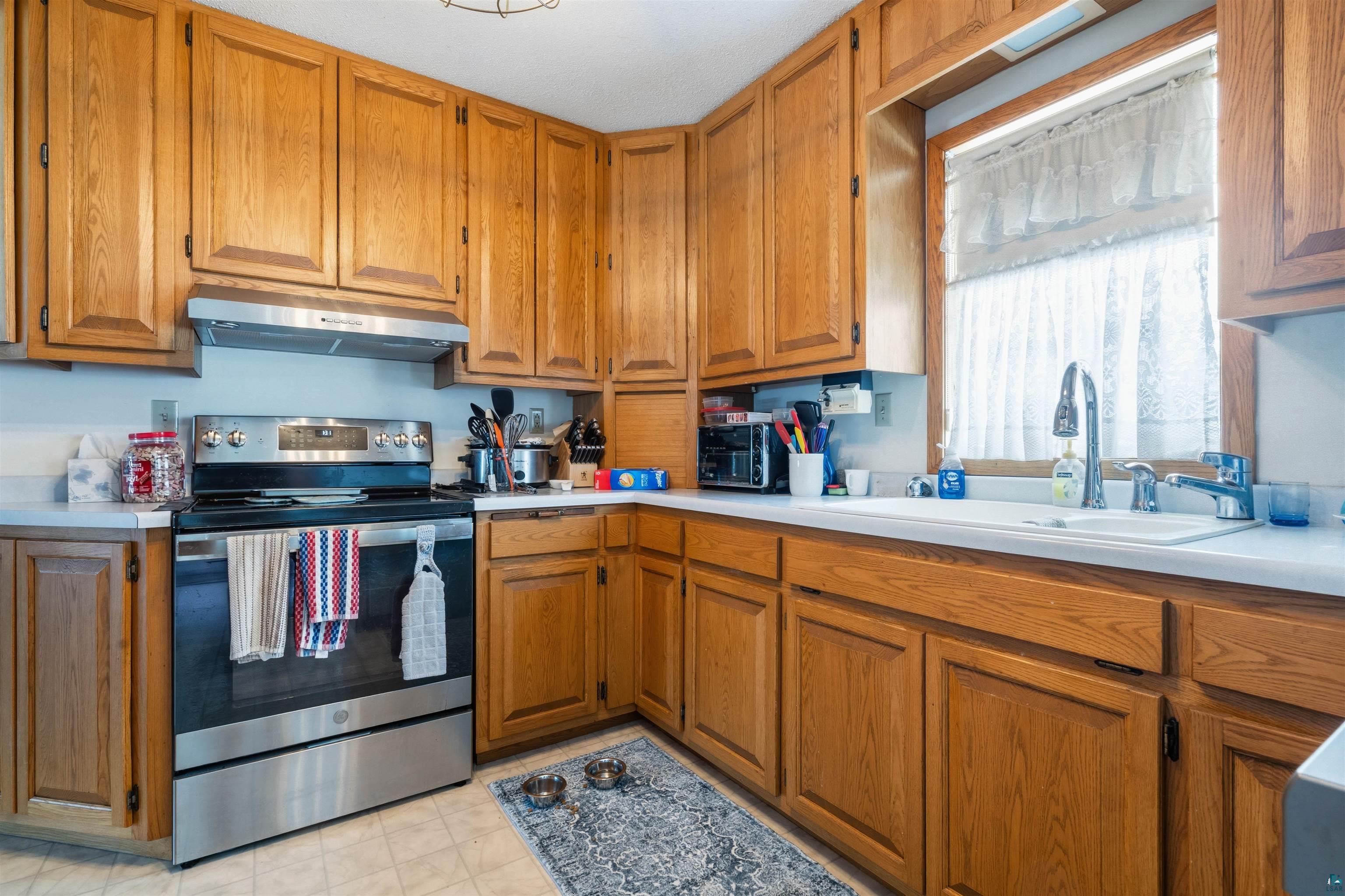 1580 Olsonville Road Carlton, MN 55718 - Photo 7 of 30 Kitchen with stainless steel electric stove, light countertops, and wood finish cabinets