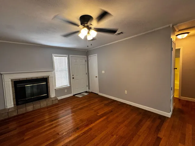 a view of an empty room with wooden floor fireplace and a window