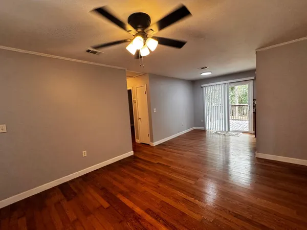an empty room with wooden floor and windows