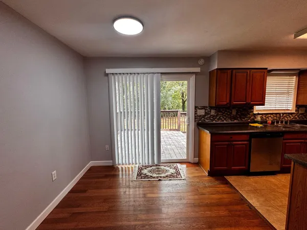 an empty room with wooden floor and black appliances