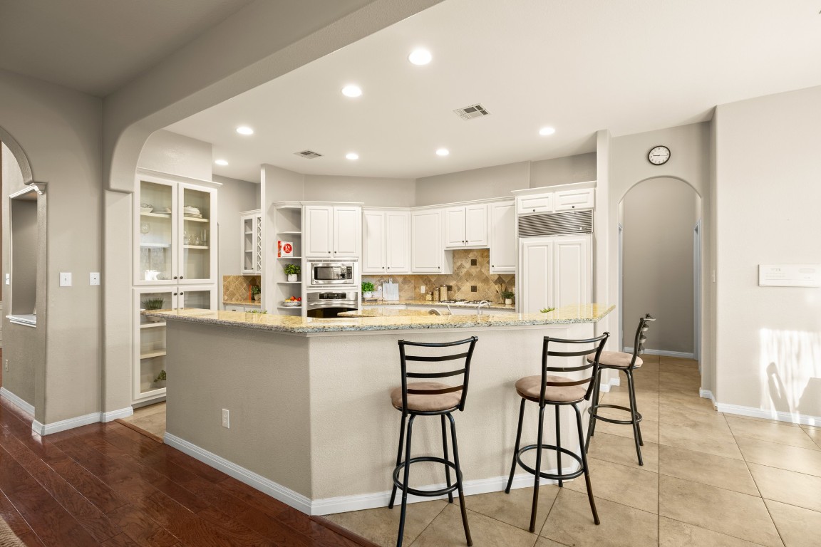 8021 Tahoe Parke Circle Austin, TX 78726 - Photo 11 of 33 a kitchen with kitchen island wooden cabinets and refrigerator