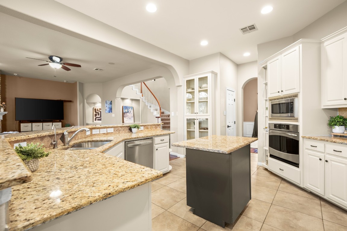 8021 Tahoe Parke Circle Austin, TX 78726 - Photo 12 of 33 a large kitchen with kitchen island granite countertop a stove refrigerator and cabinets