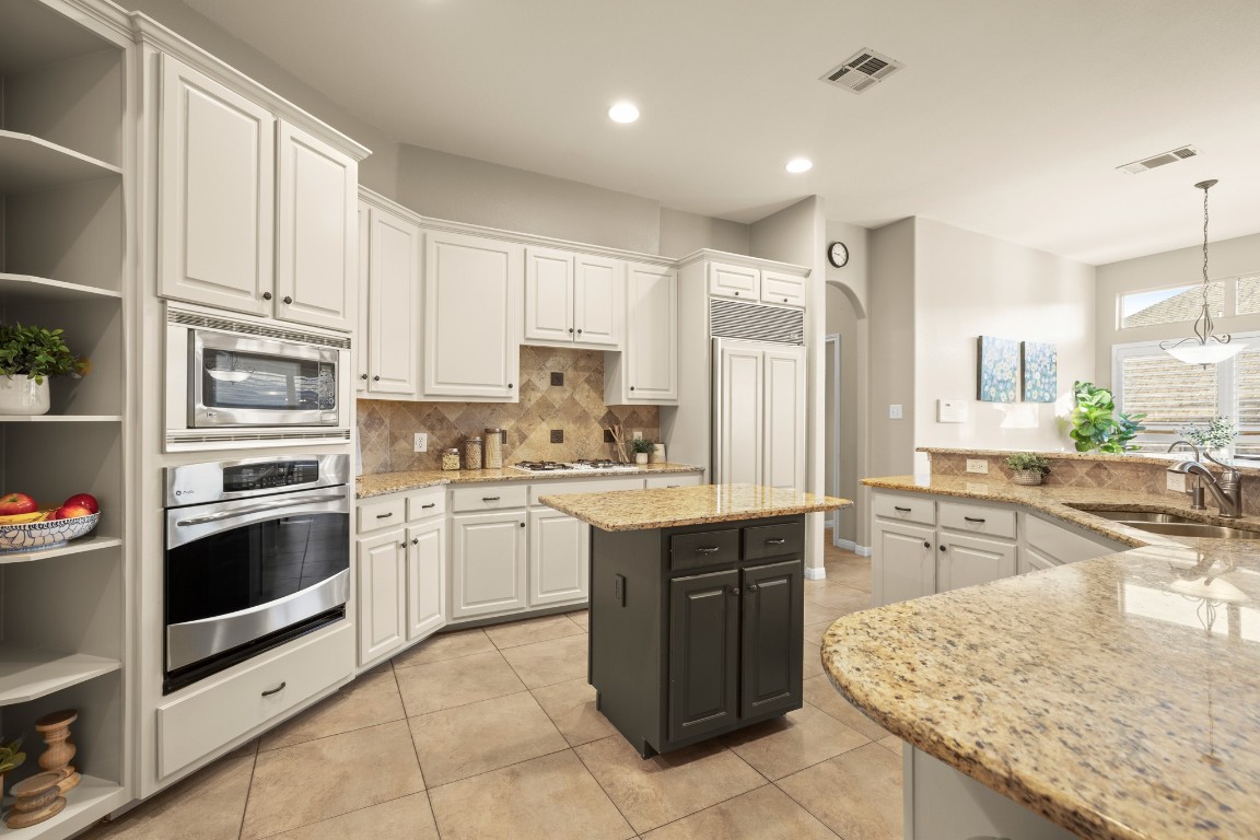 8021 Tahoe Parke Circle Austin, TX 78726 - Photo 14 of 33 a kitchen with stainless steel appliances granite countertop a stove top oven a sink dishwasher and a refrigerator with wooden cabinets