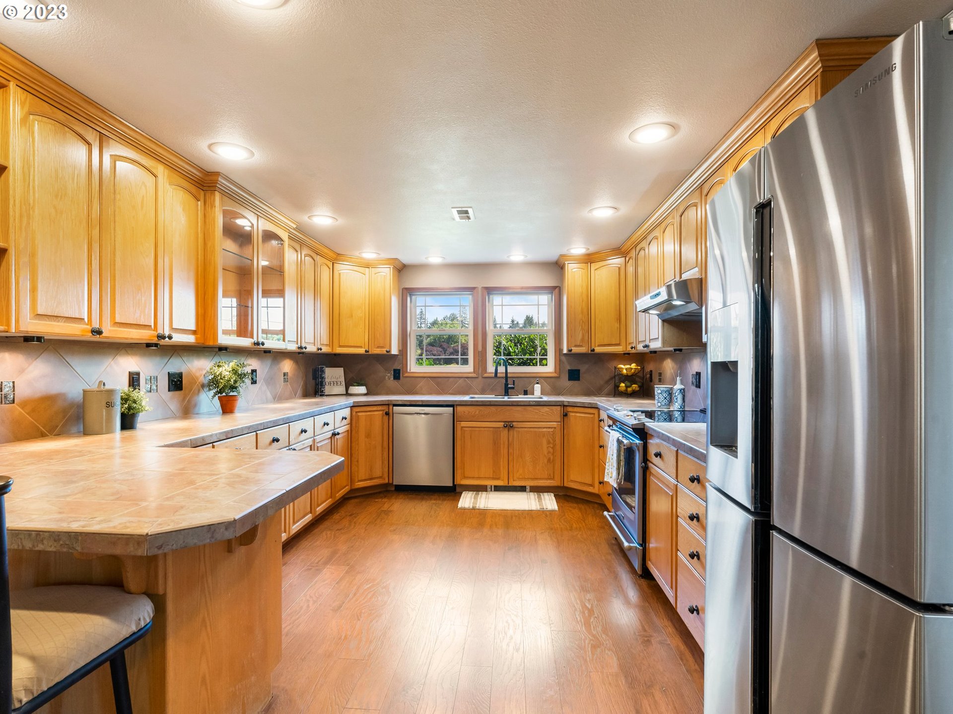 22114 Northeast 29th Avenue Ridgefield, WA 98642 - Photo 10 of 46 a large kitchen with stainless steel appliances granite countertop a refrigerator a sink dishwasher a stove and white countertops with wooden floor