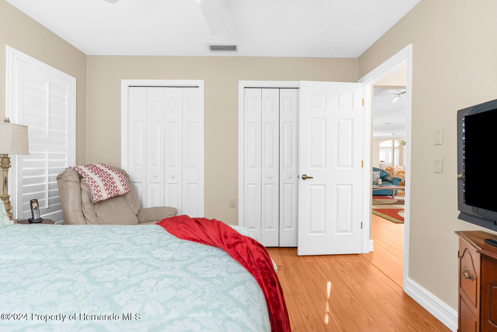 7424 Harvard Hills Place Spring Hill, FL 34606 - Photo 27 of 38 a bedroom with a bed and a flat tv screen on dresser
