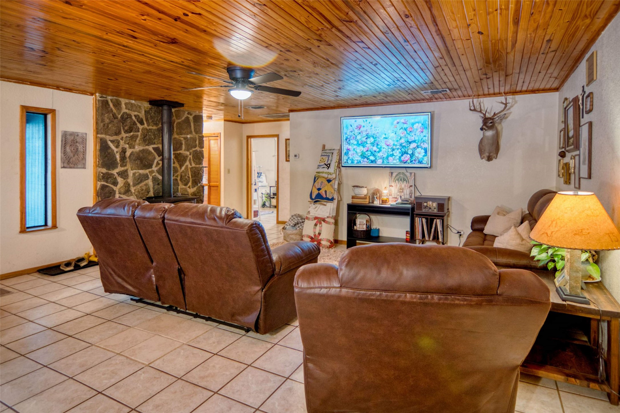 904 Bluebonnet Road Mason, TX 76856 - Photo 11 of 28 Spacious interior featuring a wood plank ceiling, a stone accent wall with a built-in stove, and tile flooring