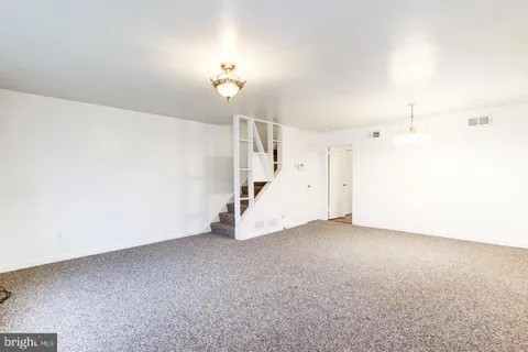 an empty room with a chandelier fan and stairs