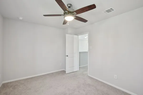an empty room with a ceiling fan and carpet