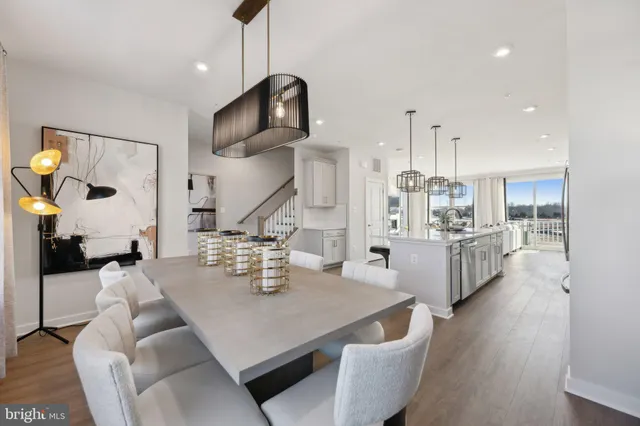 a living room with kitchen island stainless steel appliances furniture a rug kitchen and a chandelier