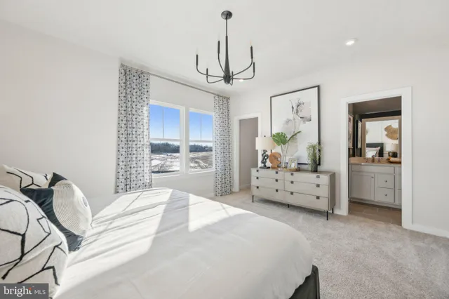 a bedroom with a bed a chandelier and a dresser