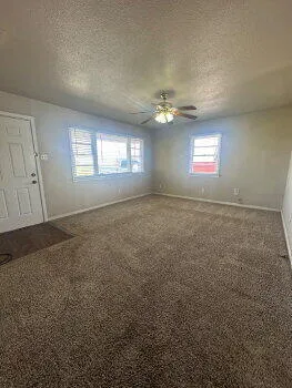 a view of empty room with windows and ceiling fan