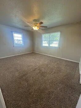 an empty room with a window and a ceiling fan