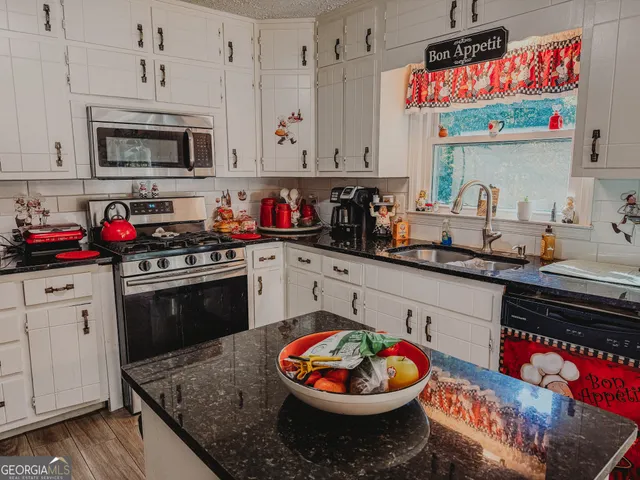 a kitchen with stainless steel appliances granite countertop a stove a sink and a microwave