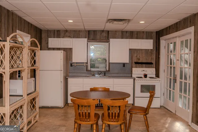 a kitchen with a refrigerator a stove a sink and a dining table with wooden floor