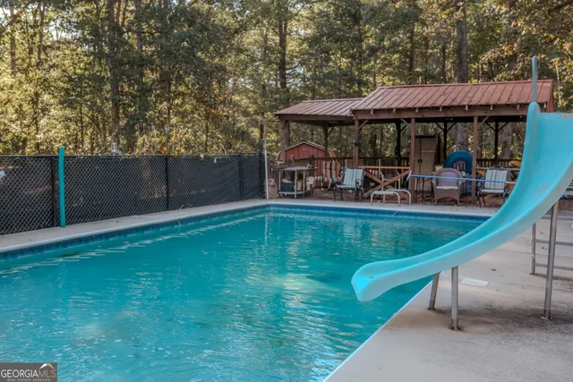 a view of a wooden house with large trees and playing area