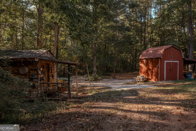 a view of a wooden house with a yard and large trees