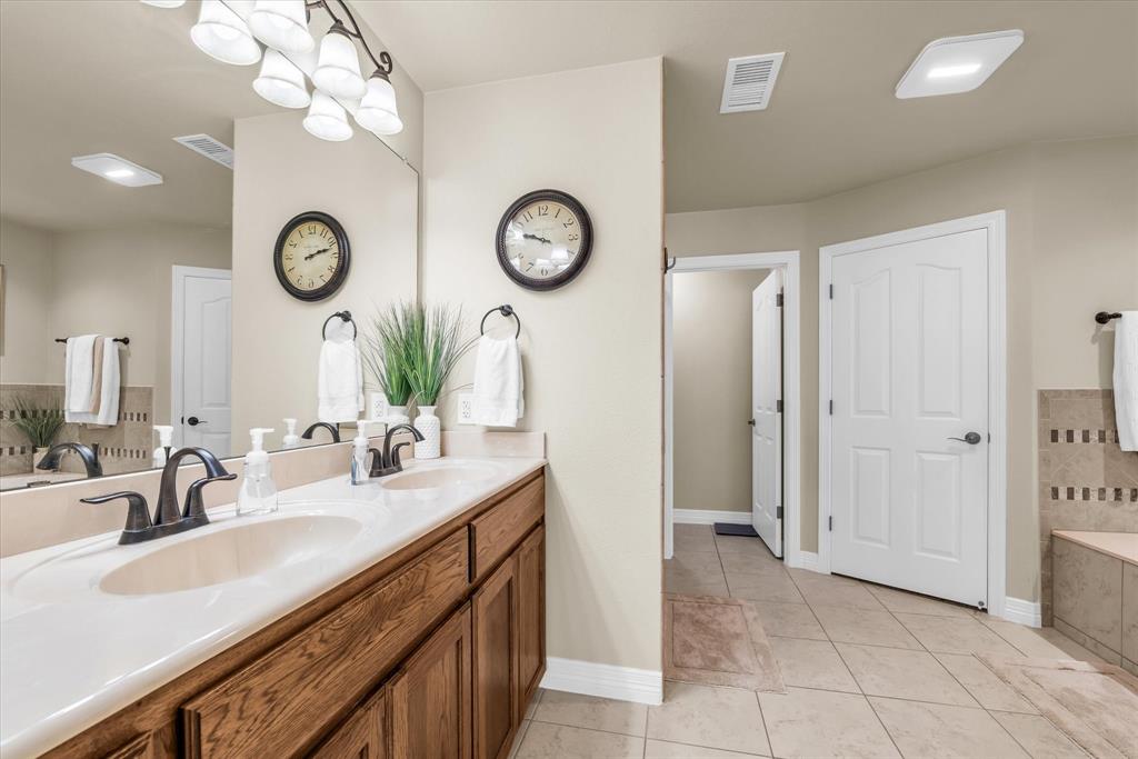 910 Springdale Lane Lorena, TX 76655 - Photo 15 of 39 Dual vanity with integrated white sinks and bronze-finish faucets set against a full-width mirror