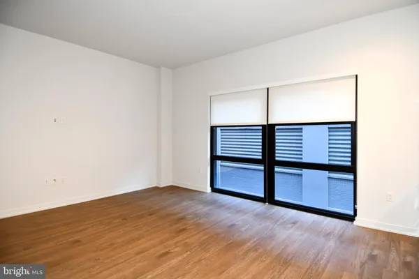 an empty room with wooden floor cabinet and windows