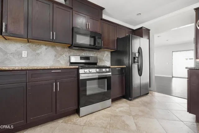 a kitchen with granite countertop a stove cabinets and stainless steel appliances