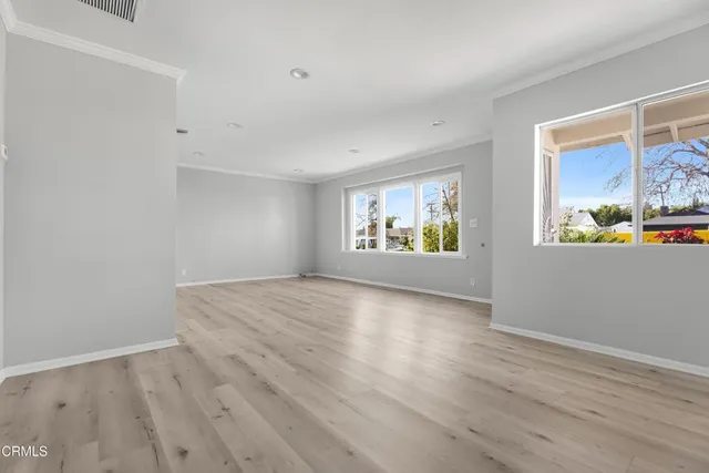 a view of an empty room with window and wooden floor