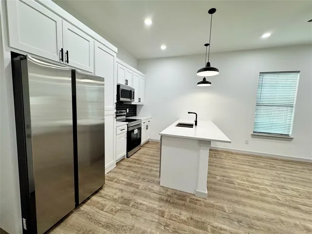 a kitchen with kitchen island a counter top space wooden floor and a ceiling fan