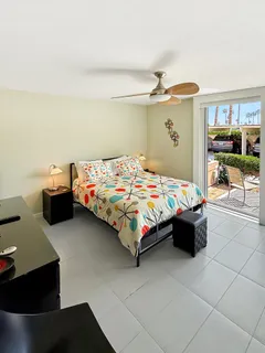 a bedroom with a bed a table and large windows