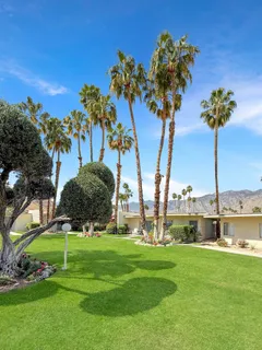 a view of a house with a yard and palm trees