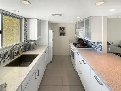 a large white kitchen with a sink and cabinets