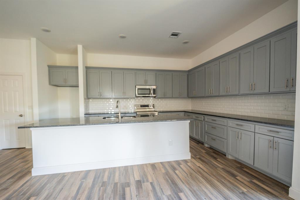 1408 Spinnaker Lane Azle, TX 76020 - Photo 3 of 8 Kitchen featuring gray shaker-style cabinetry, a built-in microwave, stainless steel range, white subway tile backsplash, and wood-finish flooring