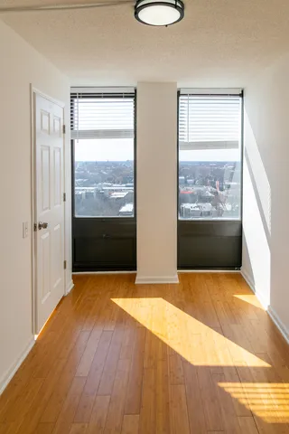 a view of an empty room with wooden floor and a window