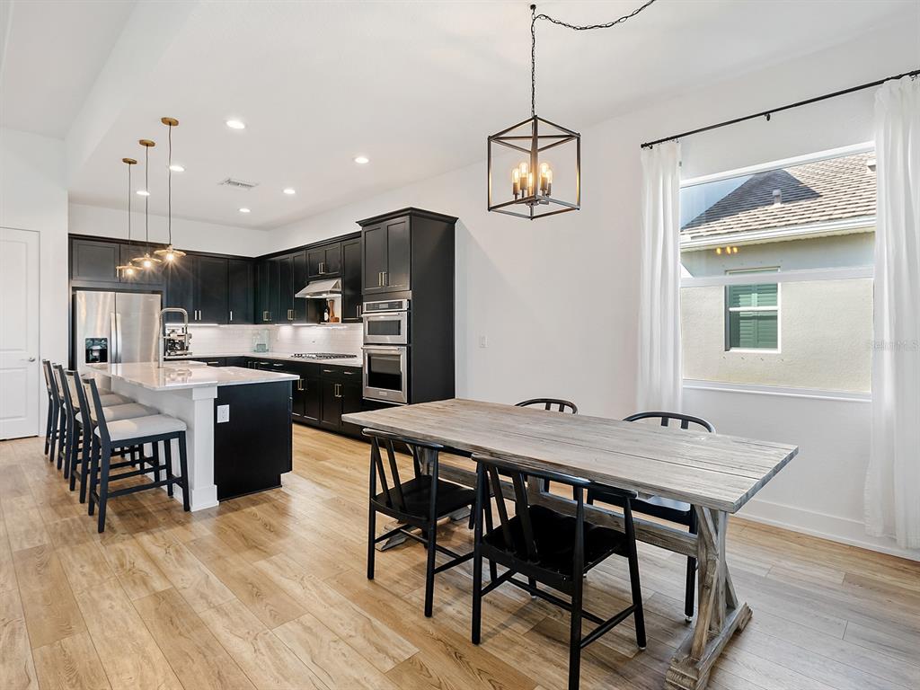 7857 Redonda Loop Lakewood Ranch, FL 34202 - Photo 16 of 51 a view of a dining room with furniture a kitchen and chandelier