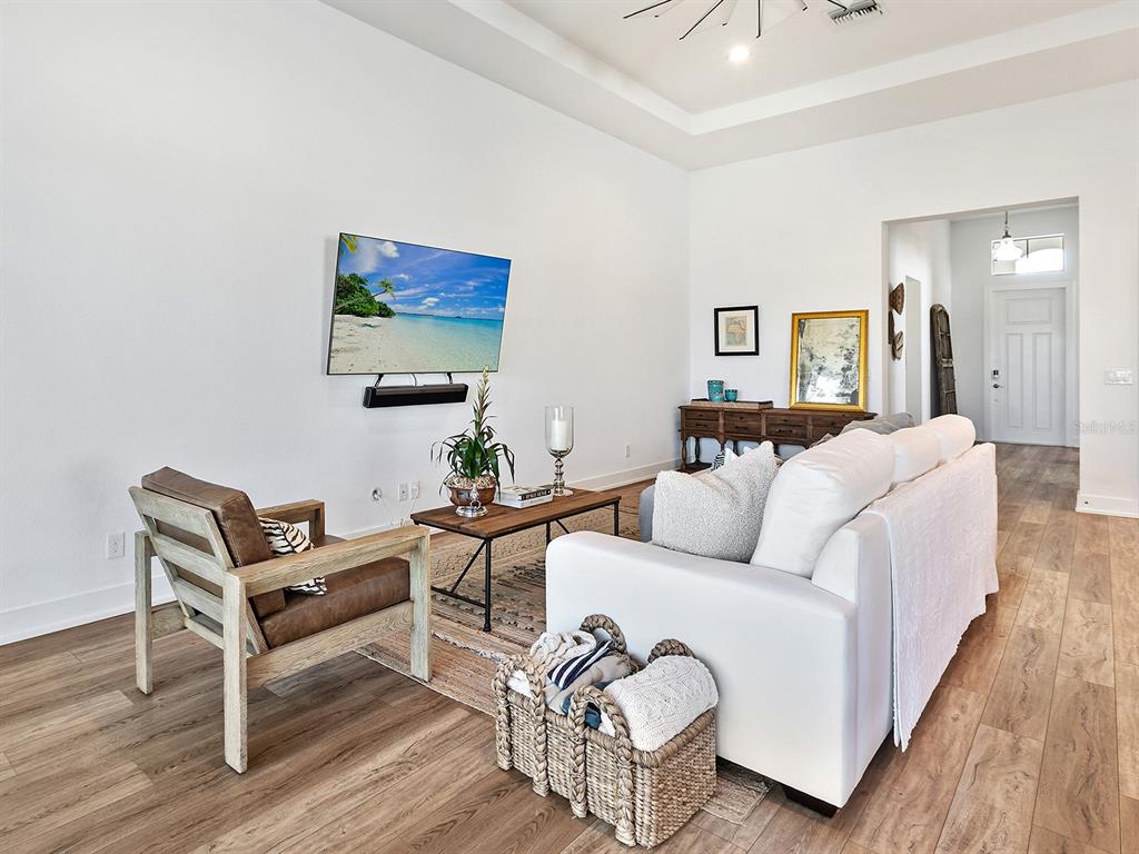 7857 Redonda Loop Lakewood Ranch, FL 34202 - Photo 7 of 51 a living room with furniture a wooden floor and a lamp