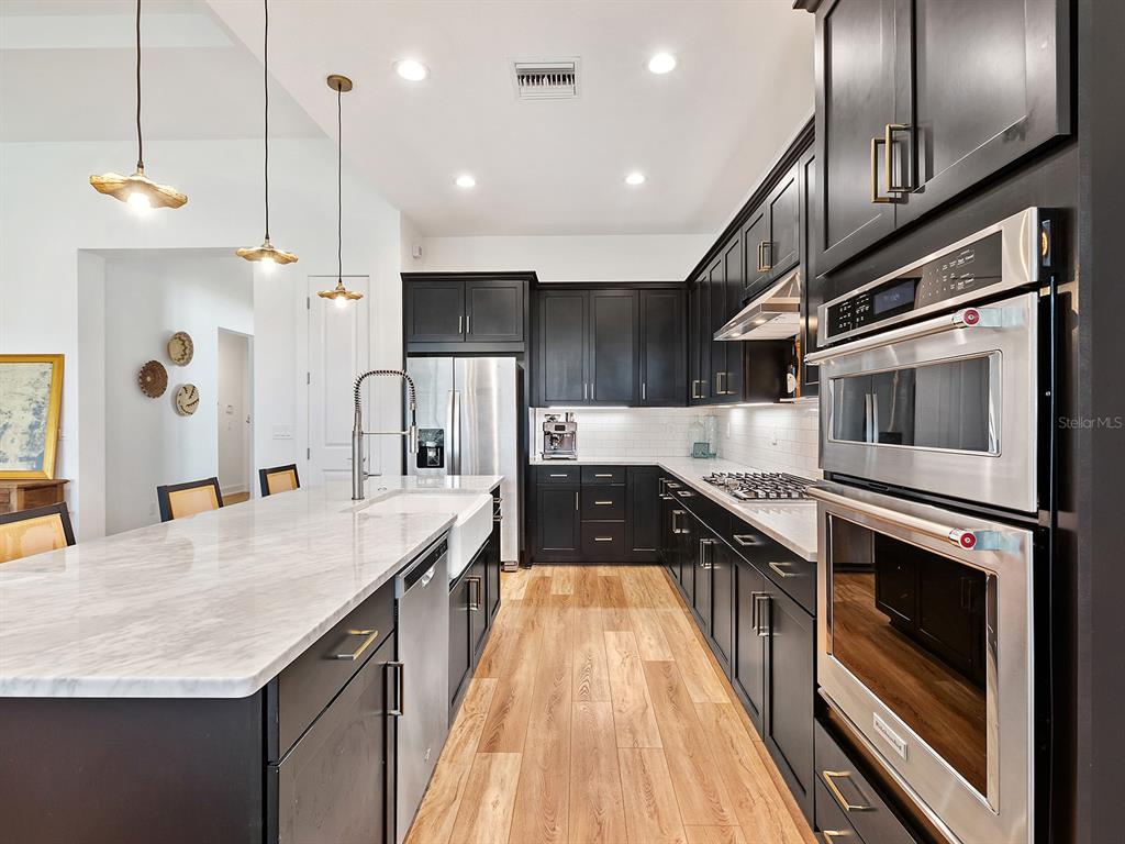 7857 Redonda Loop Lakewood Ranch, FL 34202 - Photo 9 of 51 a kitchen with stainless steel appliances granite countertop a sink a stove and a wooden floors