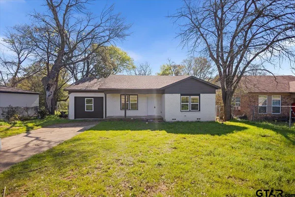 a view of a yard in front of a brick house with large windows