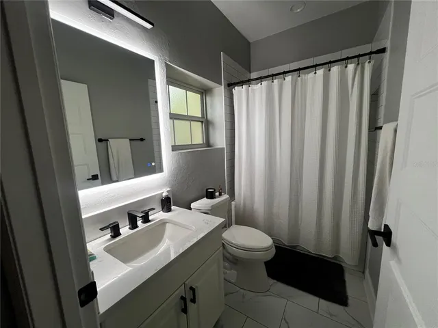 a bathroom with sink a mirror a toilet and shower